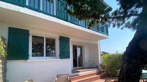 Ein Gebäude mit Balkon, Holzstühlen und einem Tisch.
