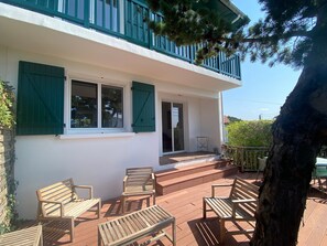 Ein Gebäude mit Balkon, Holzstühlen und einem Tisch.