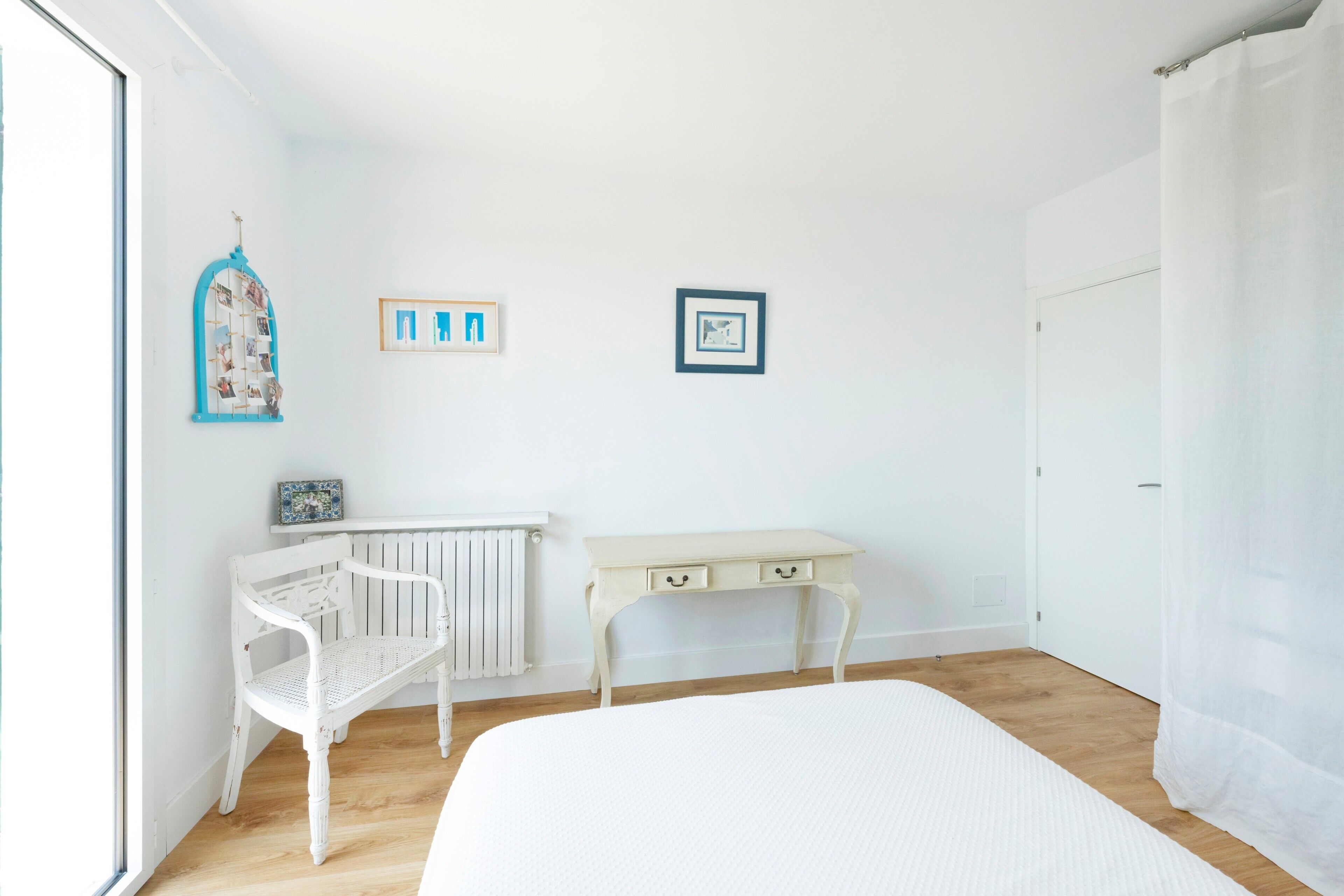 A room with a bed, a white desk, a chair, and a radiator.