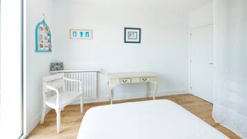 A room with a bed, a white desk, a chair, and a radiator.
