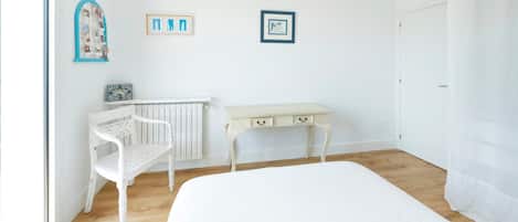 Ein Zimmer mit einem Bett, einem weißen Schreibtisch, einem Stuhl und einer Heizung.