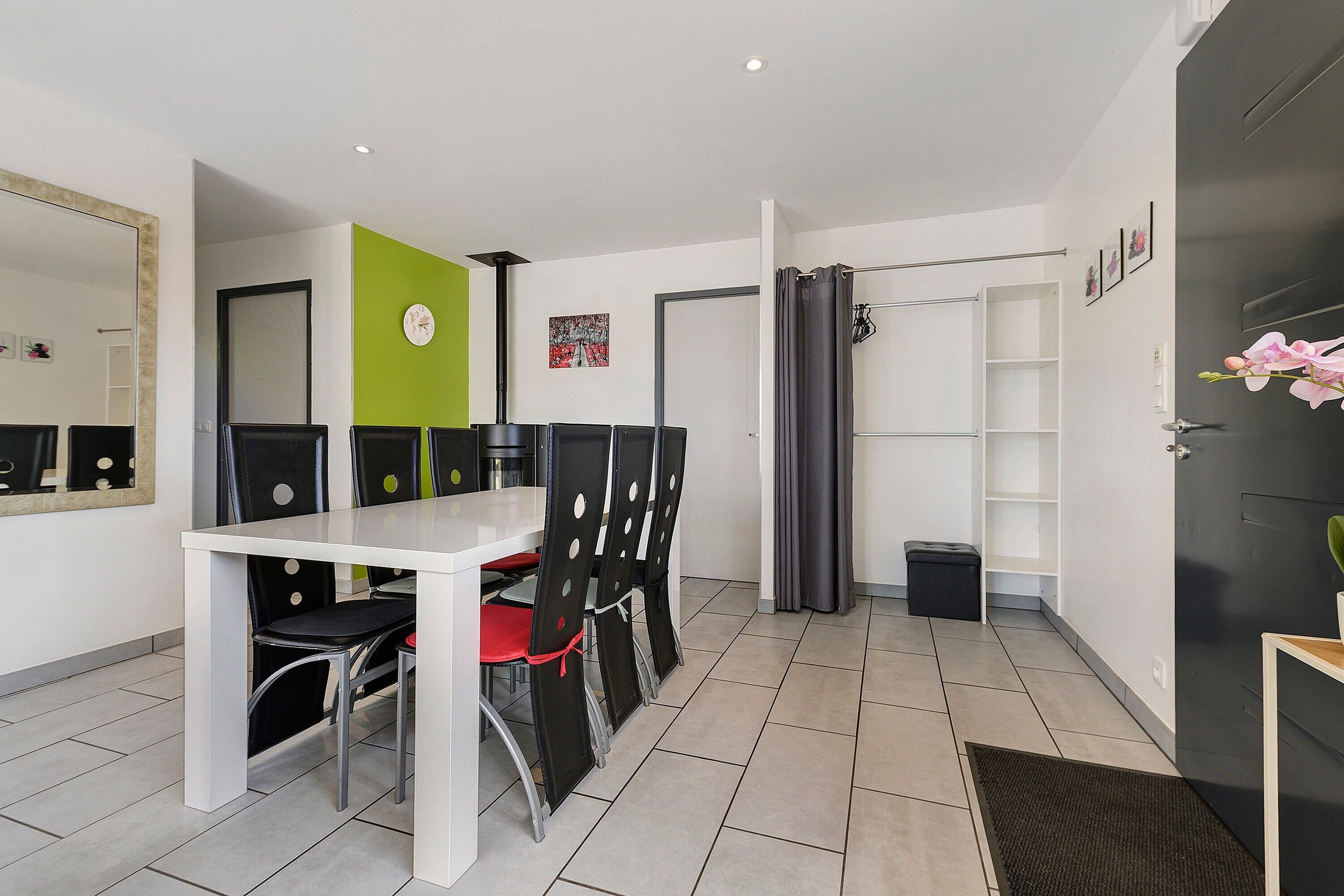 Une chambre d’hôtel moderne avec un coin repas, une porte noire, une petite poubelle et un miroir au mur.