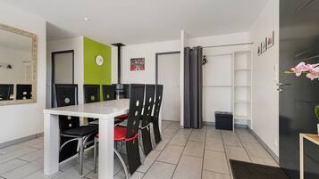Une chambre d’hôtel moderne avec un coin repas, une porte noire, une petite poubelle et un miroir au mur.