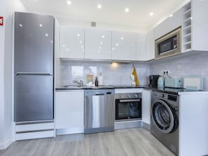 A modern kitchen with stainless steel appliances, a dishwasher, oven, and a washing machine. - Solmonte Apartment - Pool Access, Beach Close (Portimão)