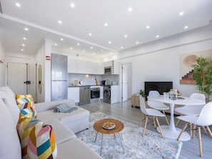 A modern living space with a sofa, dining table, and kitchen area. - Solmonte Apartment - Pool Access, Beach Close (Portimão)
