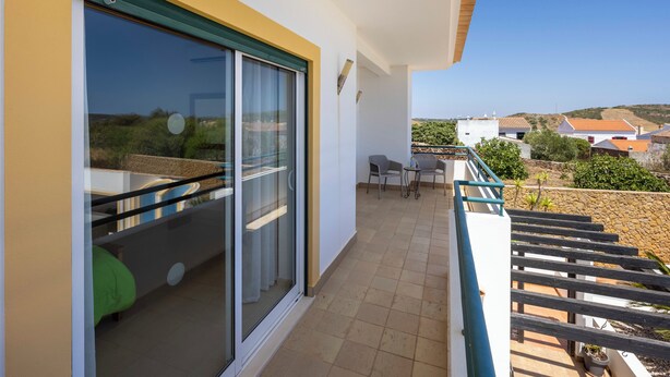 Ein Balkon mit Blick auf die Umgebung, eine Glastür und ein kleiner Tisch mit Stühlen.