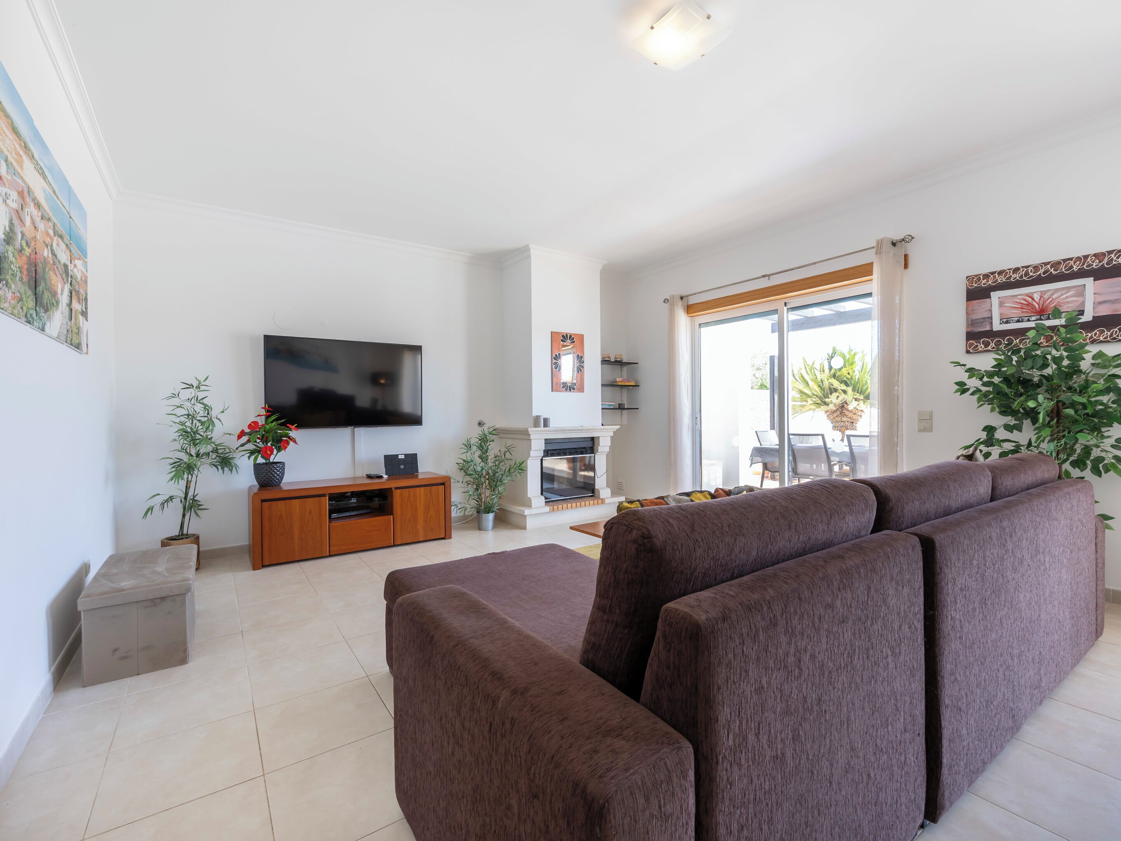 A living room with a large flat-screen TV, a sofa, a fireplace, and a dining area with a table and chairs.