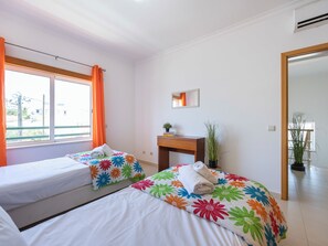 A hotel room with two beds, a desk, a mirror, and a view of the outside. - Casa Iguana - Village Apartment with Shared Pool (Budens)
