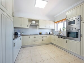 A kitchen with white cabinets, a built-in oven, and a window. - Casa Iguana - Village Apartment with Shared Pool (Budens)