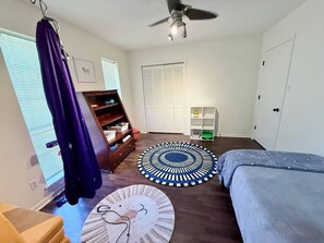 A bedroom with a bed, two rugs, a ceiling fan, a wardrobe, and a window with blinds. - Sensory-Friendly Family Retreat - Close To Park - 4-bedroom bungalow with AC (Texarkana)