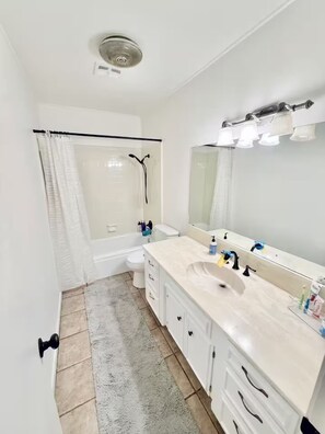Ein Badezimmer mit Badewanne, Toilette und Waschbecken mit Spiegel.