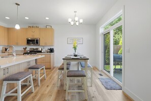 Eine moderne Küche mit Holzausstattung, einer Edelstahl-Mikrowelle und einem Essbereich mit Tisch und Stühlen.
