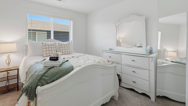 A bedroom with a bed, dresser, mirror, and bedside table. - Page Place: Modern Extended Stay in Newberg, Dog-Friendly (Newberg)