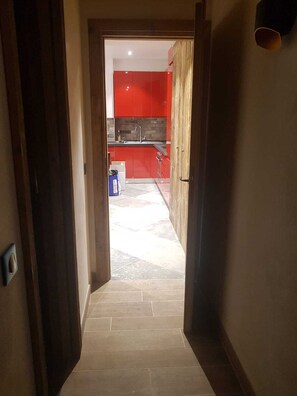 A hallway leading to a kitchen with red cabinets and a tiled floor. - Luxury 3-star Apartment Rental for 6 People (Tignes)