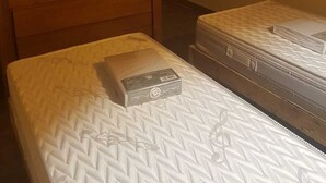 A bedroom with a TV on a wooden dresser, two beds with mattresses, and a small wall-mounted light. - Luxury 3-star Apartment Rental for 6 People (Tignes)