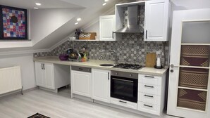 A modern kitchen with white cabinets, a gas stove, an oven, and a patterned backsplash. - Cozy 2 Seprate Bedroom Apartment in Küçükçekmece With Stunning Views (Istanbul)