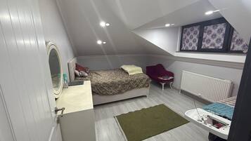 Un dormitorio con cama, una silla, un radiador y una mesita de noche con espejo.