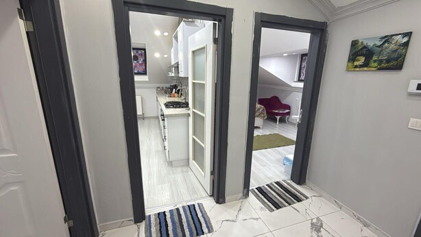 A hallway leading to a kitchen with white cabinets and a red chair. - Cozy 2 Seprate Bedroom Apartment in Küçükçekmece With Stunning Views (Istanbul)