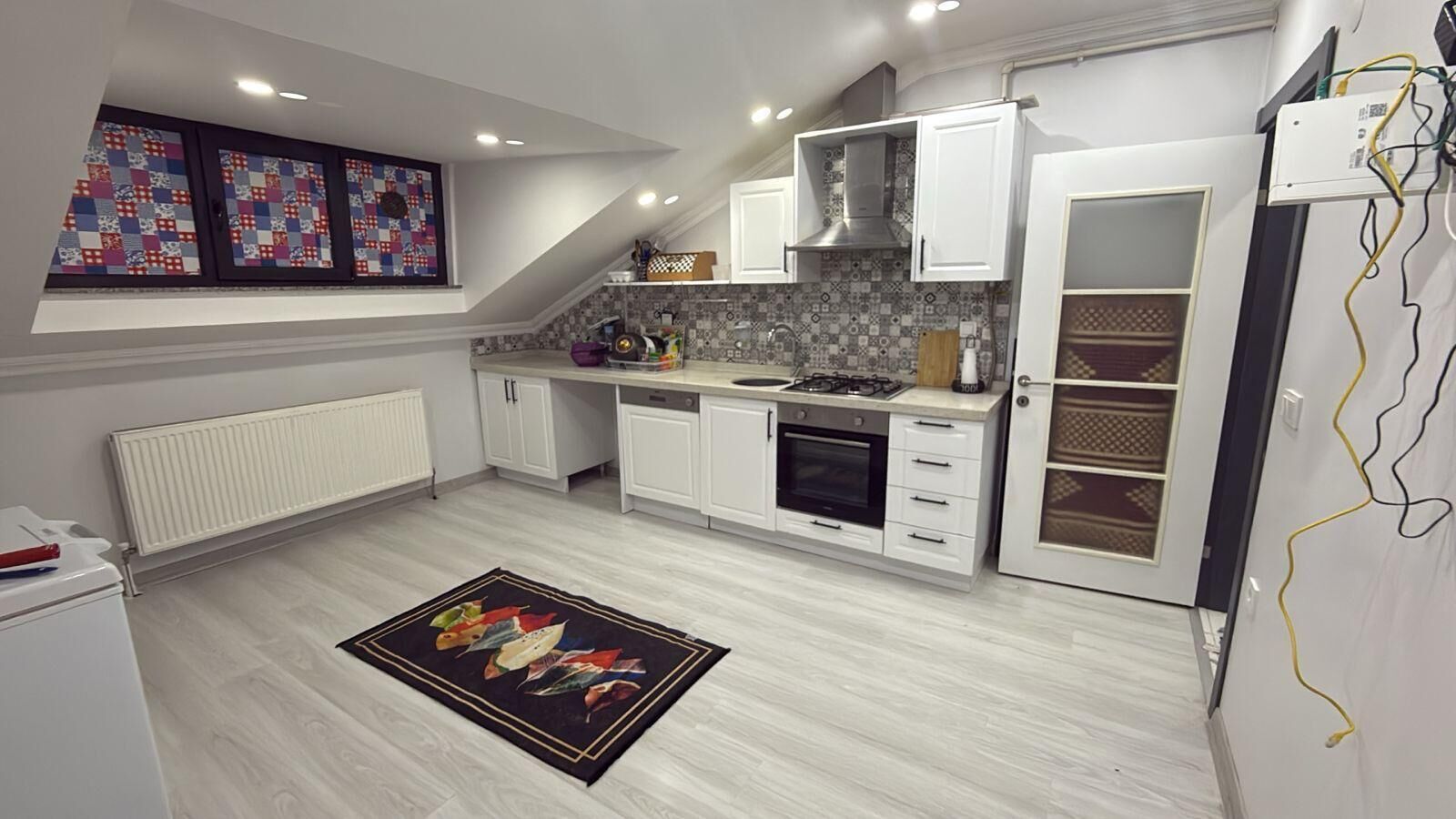 Una cocina moderna con muebles blancos, horno integrado y salpicadero de azulejos.