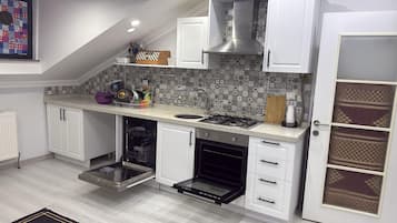 Una cocina con armarios blancos, horno empotrado, cocina a gas y salpicadero decorado.