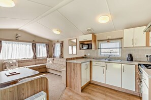 A compact RV kitchen with a dining area, a microwave, a sink, and a stove. - Host Stay Sunset Haven (Weymouth)