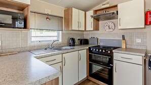 Una cocina moderna con estufa, horno, microondas y un reloj en la pared.