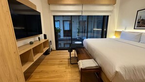 A modern hotel room with a large bed, a TV, a small table, and a bench. - w Enchanting Loft in the Heart of Roma Sur (Mexico City)