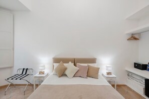 Een slaapkamer met een bed, twee nachtkastjes, een hanglamp, een radiator en een handdoekhouder.
