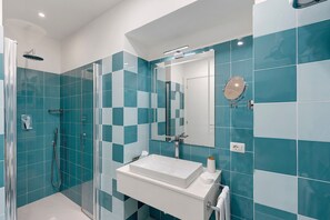 A modern bathroom with a glass-enclosed shower, a white sink, and a mirror.