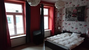 A bedroom with a bed, a window with curtains, a radiator, and a wall with a patterned wallpaper. - Charming studio apartment in the heart of Kraków (Kraków)