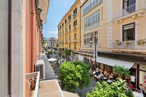 A street view with buildings, outdoor seating, and pedestrians.