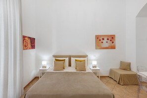 Una camera d'albergo con un letto grande, due comodini, una sedia e opere d'arte alle pareti.