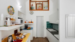 A compact kitchen with a microwave, coffee maker, and a bowl of fruit on the counter. - Sorrentina Guest House – Quadruple Room with Balcony and Wi-Fi (Sorrento)
