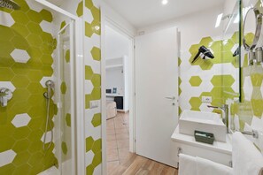 A bathroom with a shower, a sink, and a hairdryer.