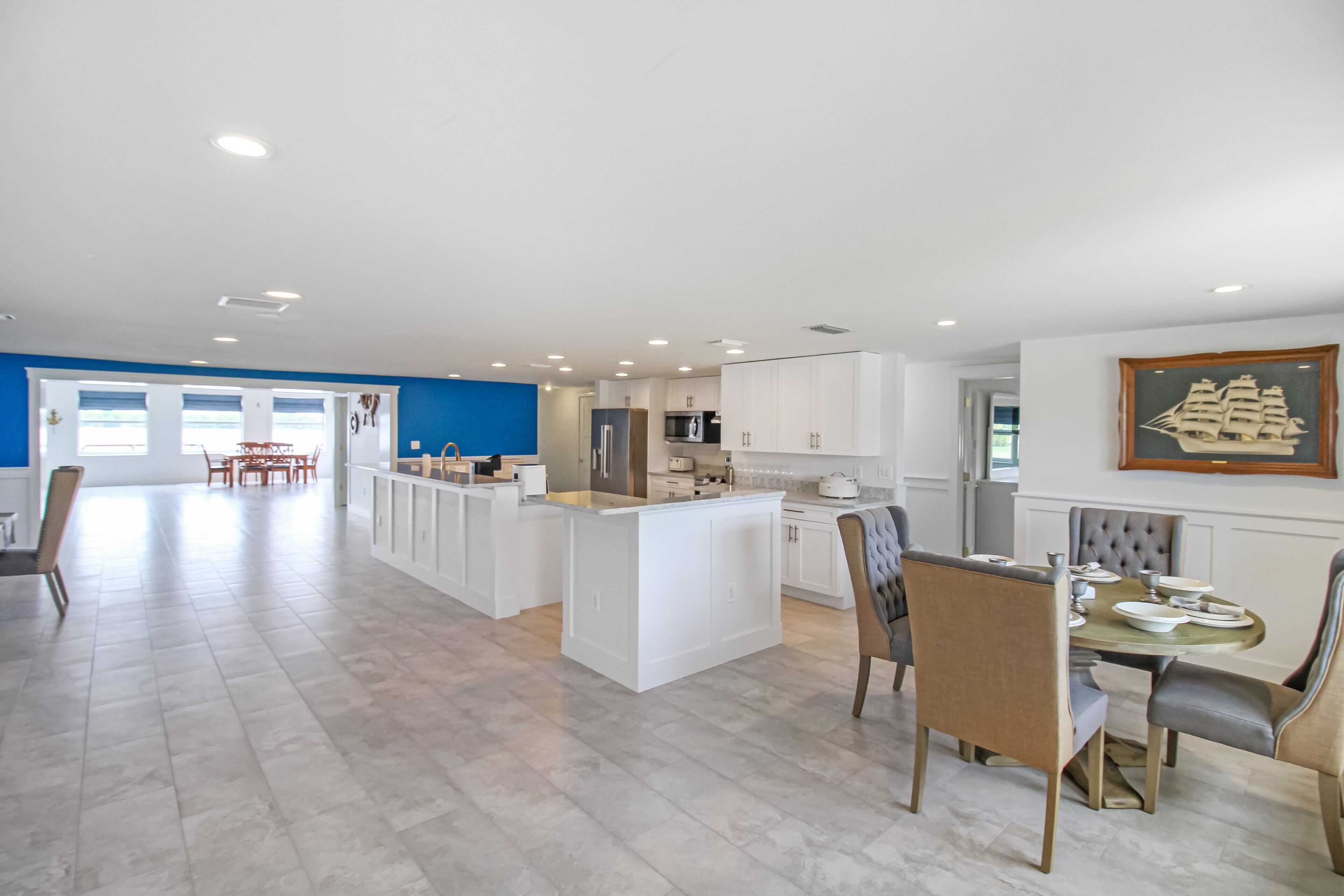 A spacious kitchen with white cabinetry, a central island, and a dining area with a table and chairs.