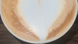 A cup of coffee with a heart-shaped latte art on a wooden table. - Best place in Nienstedten (Hamburg)