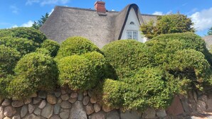 A house with a steeply pitched roof, a chimney, and a stone wall. - Best place in Nienstedten (Hamburg)
