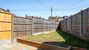 A backyard with a wooden fence, a grassy area, and a stone pathway. - Perfect Booking 4 Bed Home With Parking for 2 (Bristol)