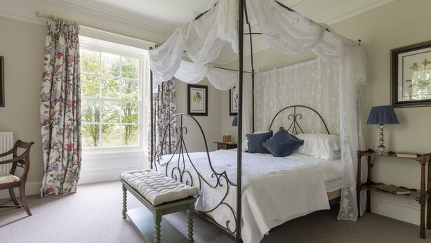 A four-poster canopy bed with a bench, a chair, and a bedside table with a lamp. - Sunderland Farmhouse - Sleeping 8 Guests in 4 Bedrooms, Dog Friendly (Galashiels)