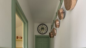 A hallway with a green door, a clock, and copper pots on the wall. - Sunderland Farmhouse - Sleeping 8 Guests in 4 Bedrooms, Dog Friendly (Galashiels)