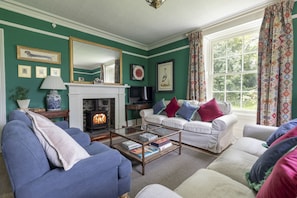 A living room with a fireplace, sofas, and a television. - Sunderland Farmhouse - Sleeping 8 Guests in 4 Bedrooms, Dog Friendly (Galashiels)
