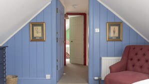 A room with a sloped ceiling, a red chair, a framed picture, and a radiator. - Sunderland Farmhouse - Sleeping 8 Guests in 4 Bedrooms, Dog Friendly (Galashiels)