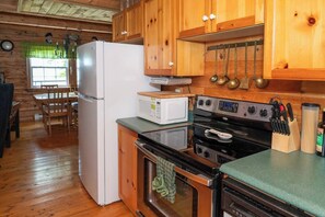 A kitchen with wooden cabinets, a refrigerator, a microwave, a stove, and a sink.