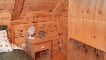 Une pièce de style cabane en bois, comprenant un lit, une table de chevet et une étagère.