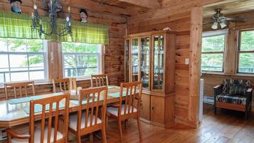 L’intérieur d’un chalet en bois, avec une table à manger, des chaises, un buffet et une fenêtre.