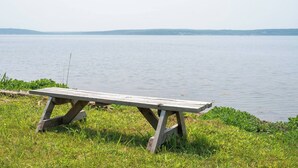 Un banco de madera junto a un lago tranquilo con orillas cubiertas de hierba.