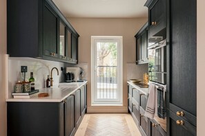 A kitchen with dark cabinetry, a white countertop, and a view through a door to an outdoor balcony.