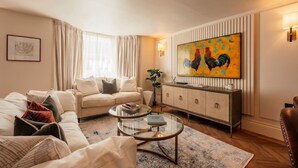 A living room with a sofa, a coffee table, and a painting on the wall. - Beautiful Fulham Apartment with Aircon (Greater London)