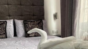 Una cama con un edredón con forma de cisne, un cabecero y almohadas estampadas.