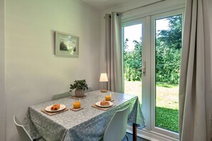 A dining table with a floral tablecloth, two plates with food and drinks, a lamp, and a potted plant. - Brockwood (Bradworthy)